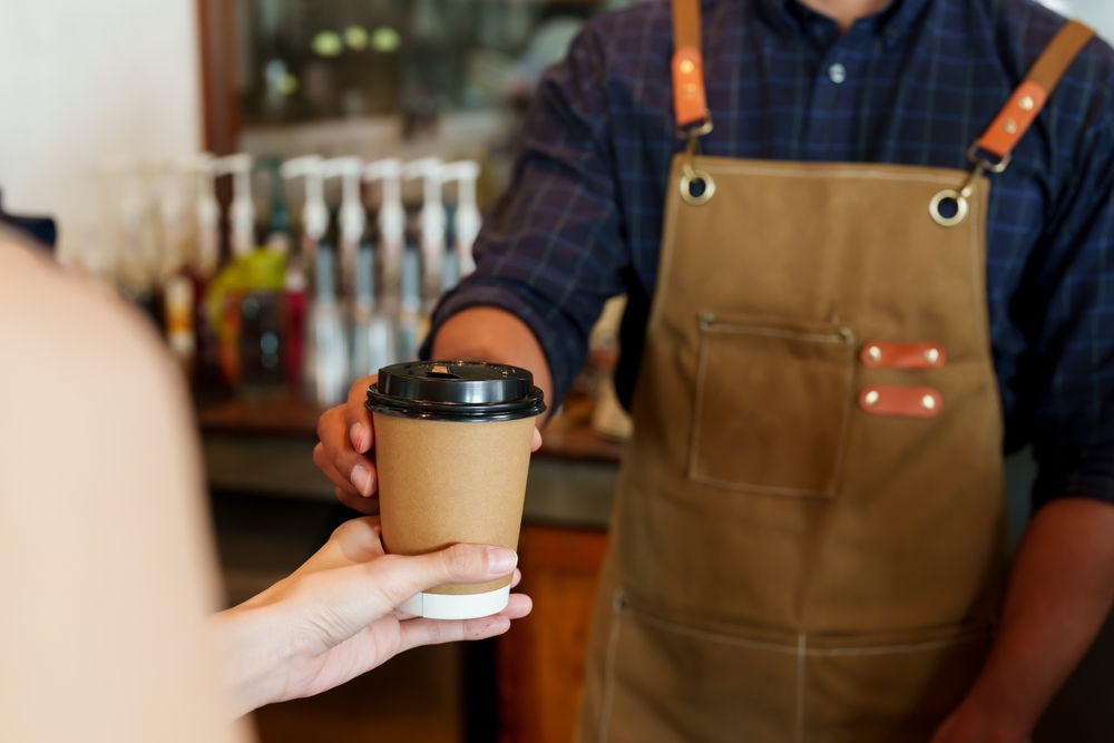 บาริสต้าในร้านคาเฟ่เสิร์ฟเครื่องดื่มให้ลูกค้า